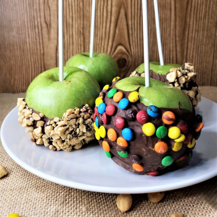 A plate for serving chocolate dipped apples decorated with nuts and candies