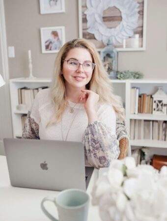 woman at a desk researching affiliate programs for bloggers, writing in a notebook next to her open laptop