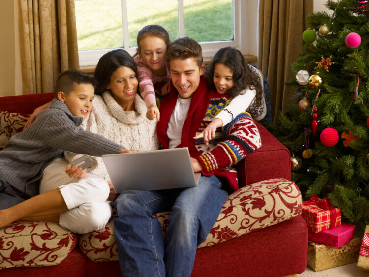 family in Christmas-decorate room looking happily at their laptop family in Christmas-decorate room looking happily at their laptop