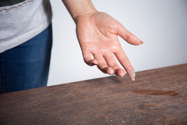 woman running finger along a dusty tabletop, wondering why is my house so dusty woman running finger along a dusty tabletop