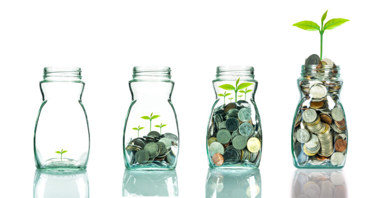 Four glass jars filled with increasing amounts of coins, each with a small green sprout growing larger, showing savings growing over time Four glass jars filled with increasing amounts of coins, each with a small green sprout growing larger, showing savings growing over time